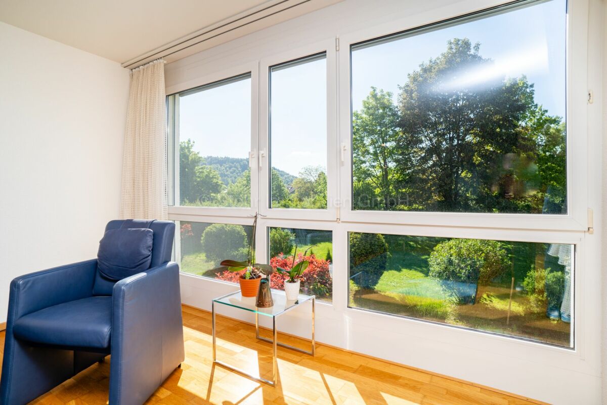Heller Wohnraum mit großem Fenster und Ausblick ins Grüne