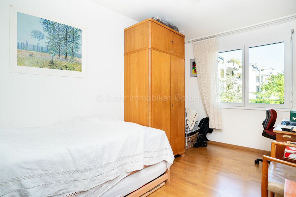 Helles Schlafzimmer mit Holzschrank und Blick ins Grüne