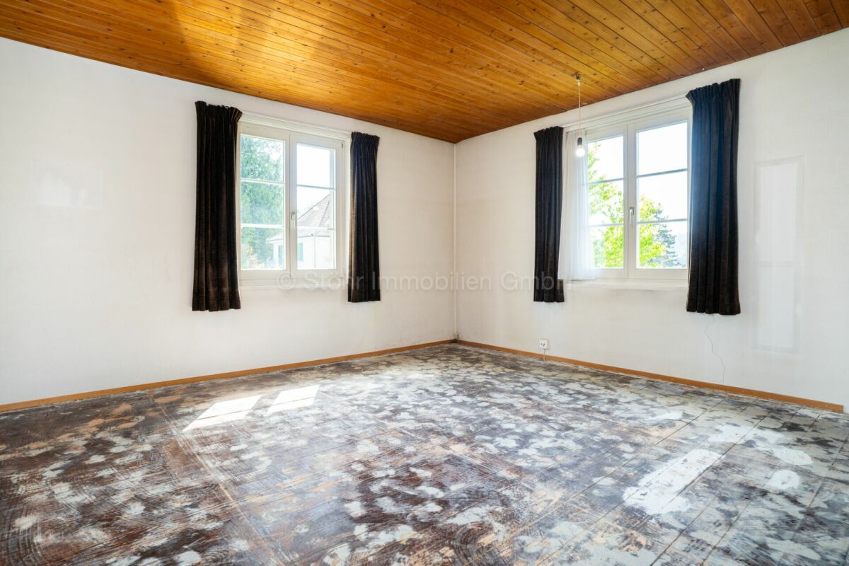 Heller leerer Raum mit Holzdecke und zwei Fenstern