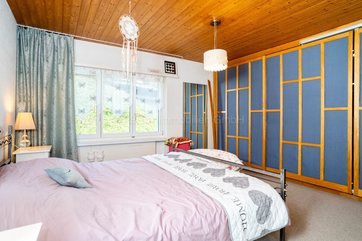Gemütliches Schlafzimmer mit Holzdecke und blauem Schrank