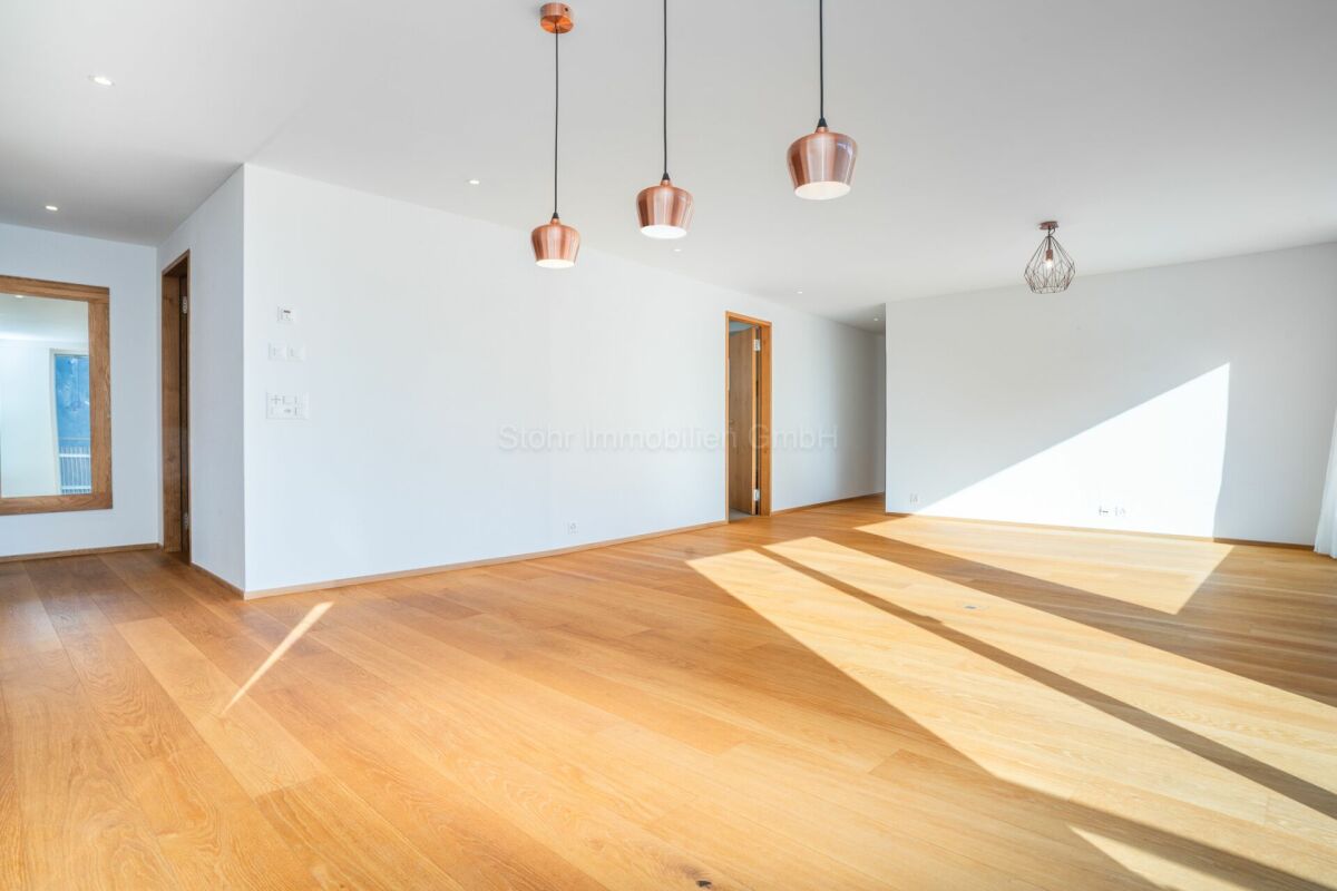 Heller leerer Wohnraum mit Holzfußboden und Pendelleuchten
