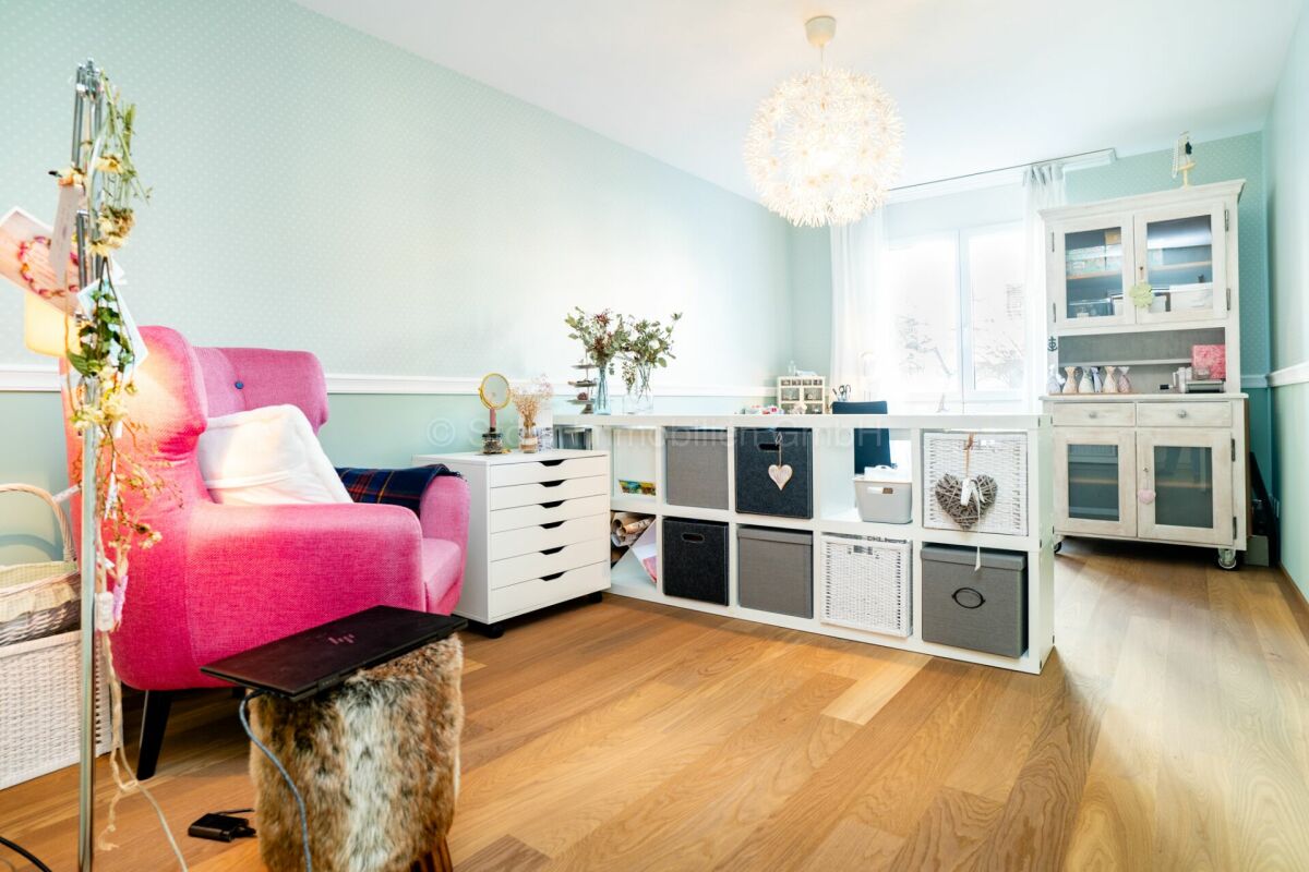 Helles, liebevoll eingerichtetes Zimmer mit rosa Sessel und mintfarbenen Wänden
