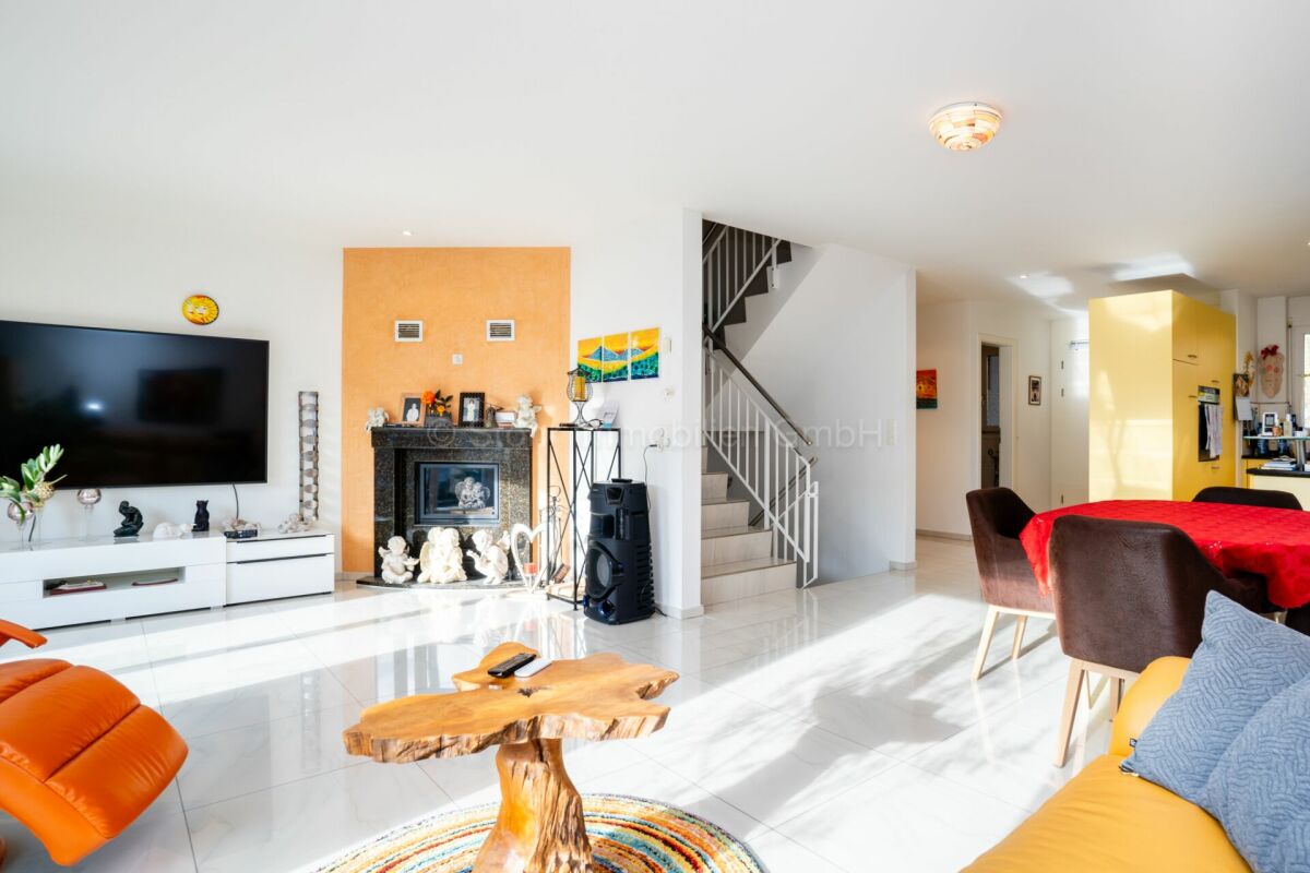 Modernes, helles Wohnzimmer mit offener Essbereichzone und Treppe