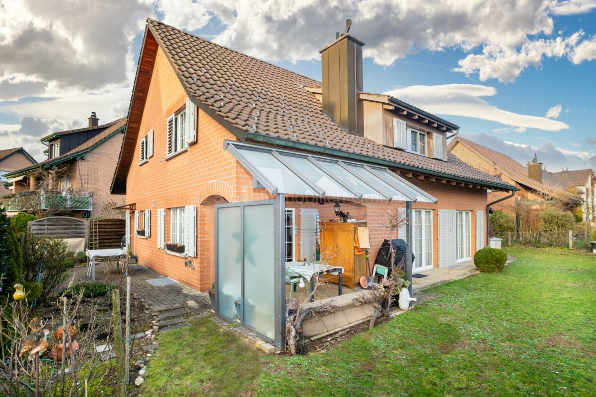 Gartenseite eines Einfamilienhauses mit Wintergarten