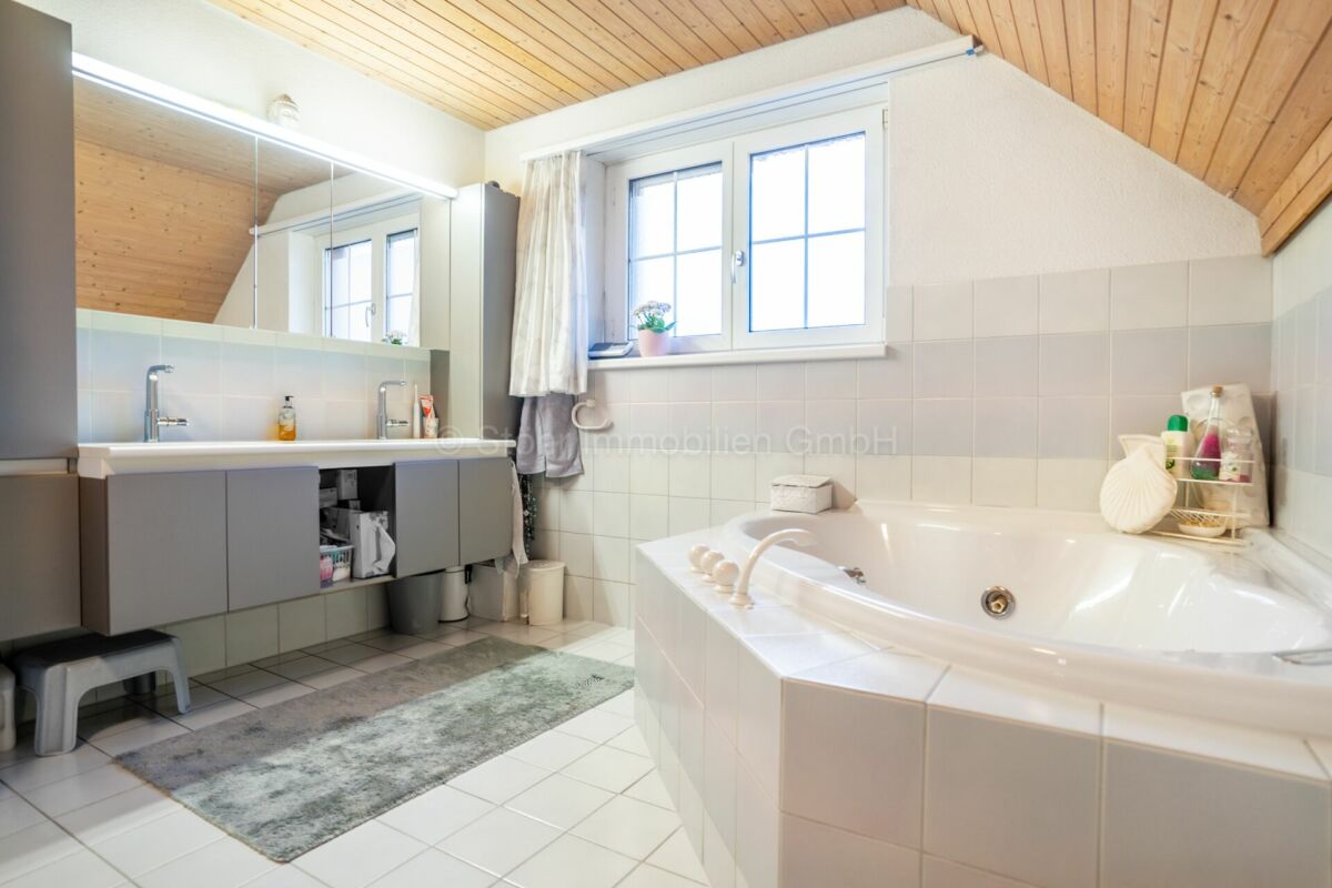 Helles Badezimmer mit Badewanne und Waschtisch unter Dachschräge
