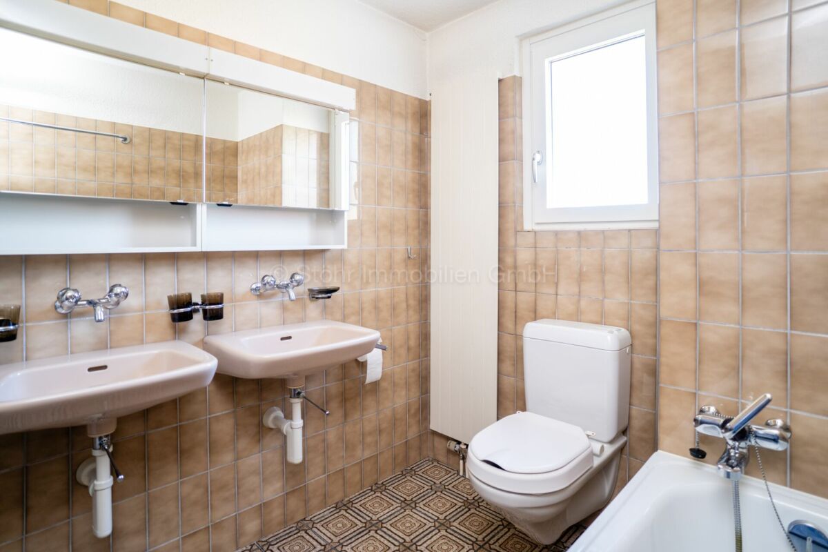 Kleines helles Badezimmer mit Doppelwaschbecken und WC