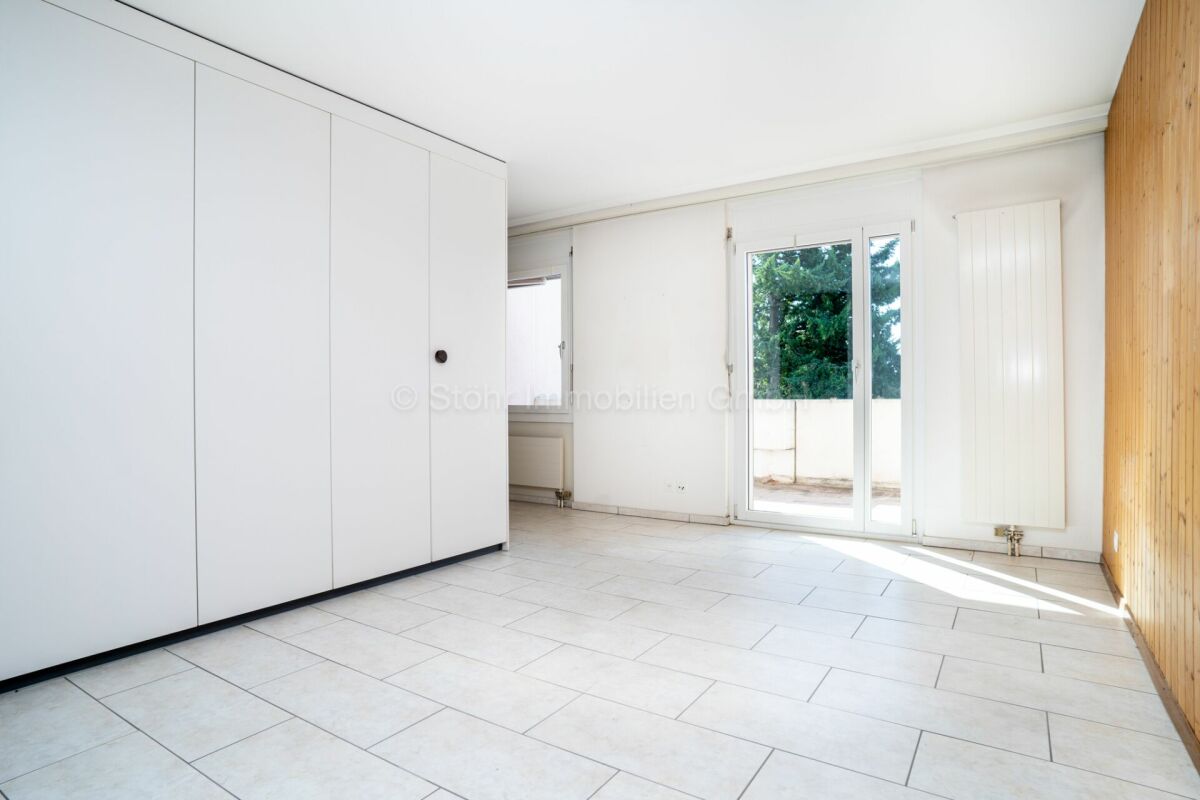 Helles, nahezu leeres Zimmer mit Balkonzugang und Einbauschrank