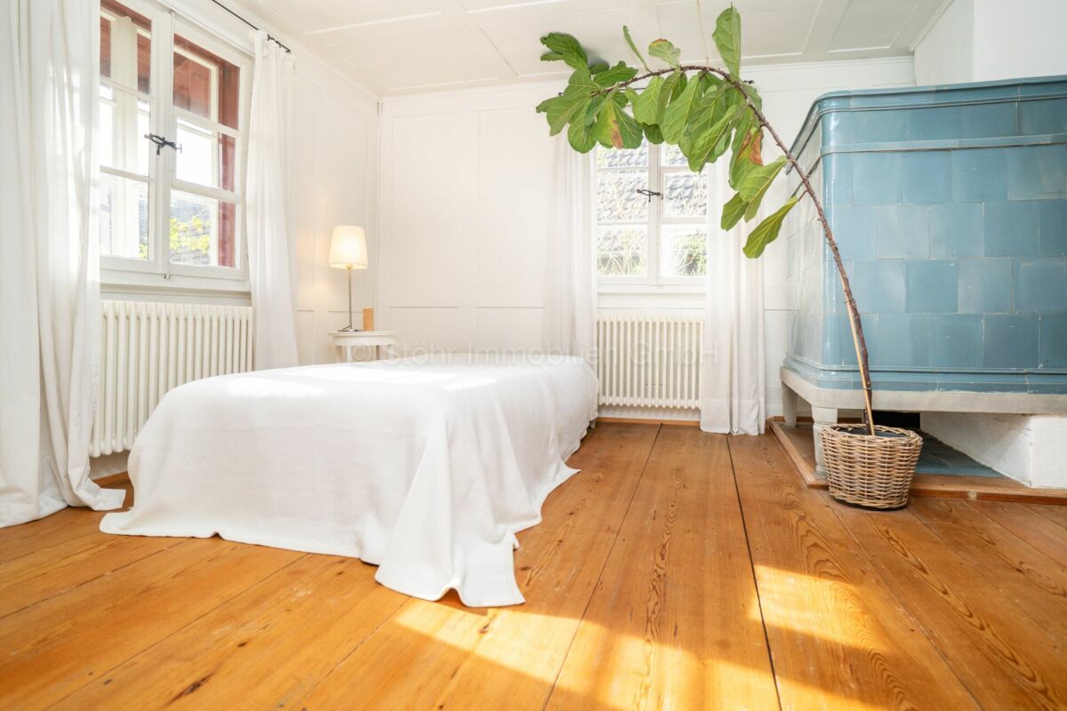 Helles Schlafzimmer mit Holzfußboden und Ofen