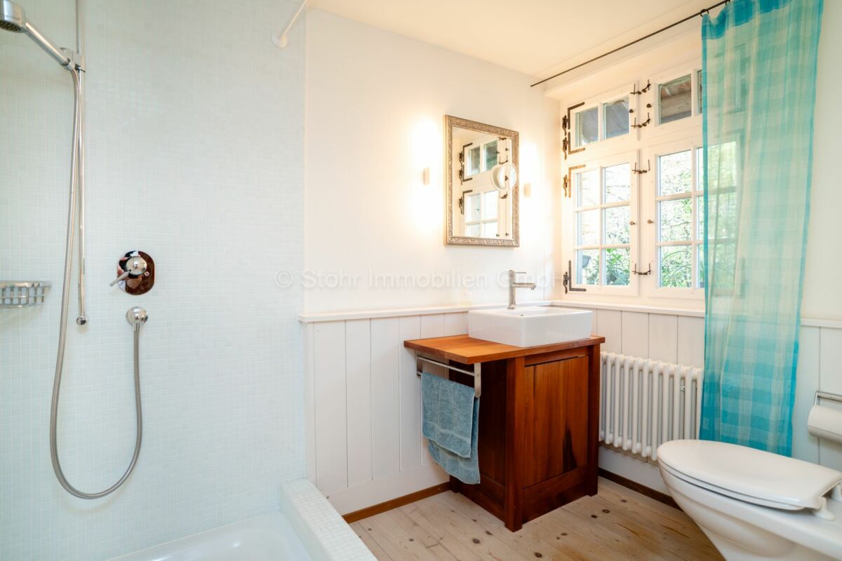 Helles Badezimmer mit Dusche, Fenster und Waschtisch