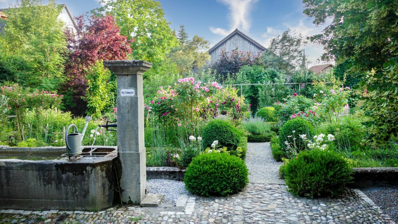 Ländlicher Garten mit Brunnen und Blumenbeeten