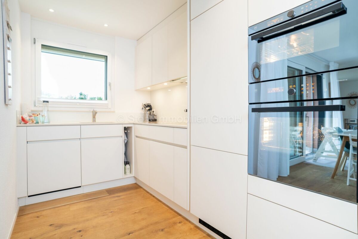 Helle, moderne Küche mit weißen Fronten und Holzfußboden