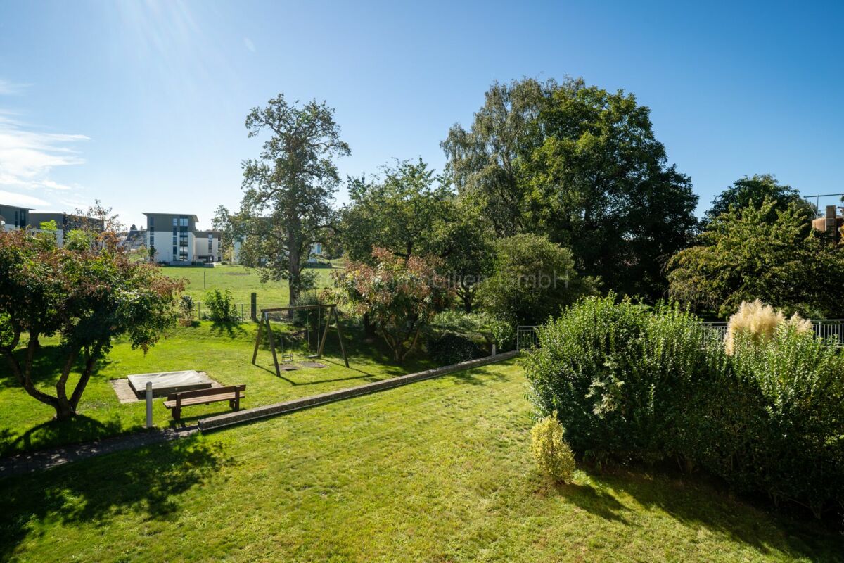 Großer grüner Garten mit Spielbereich und Blick auf Nachbargebäude