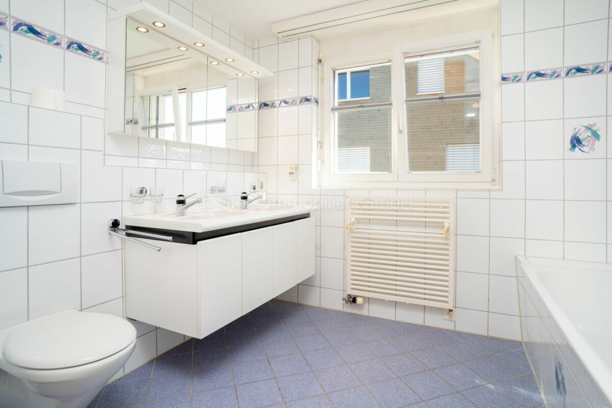 Helles Badezimmer mit Wandfliesen und Fenster