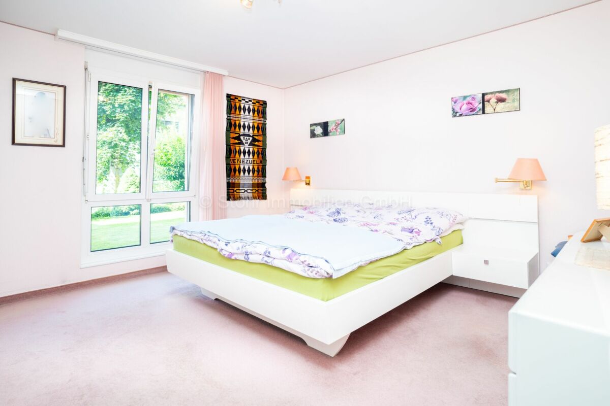 Helles Schlafzimmer mit großem Fenster und Doppelbett