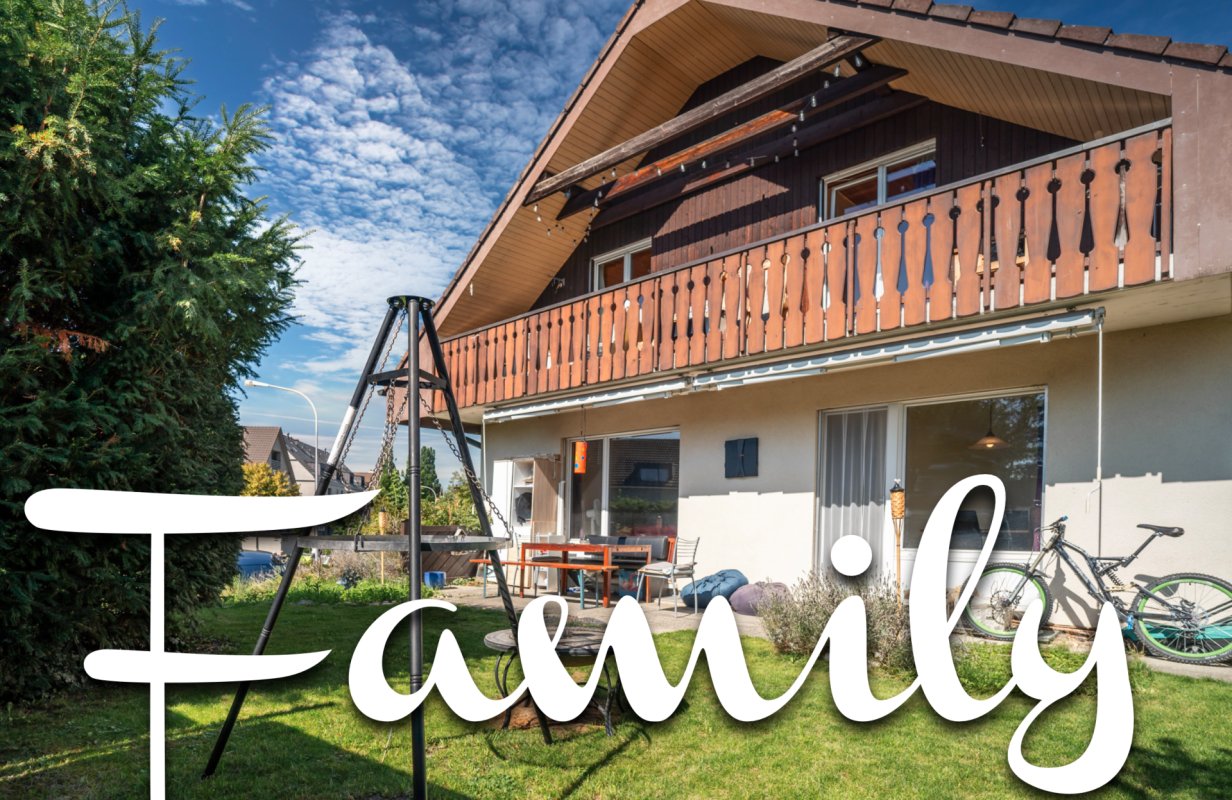 Außenansicht eines Einfamilienhauses mit Balkon und Garten