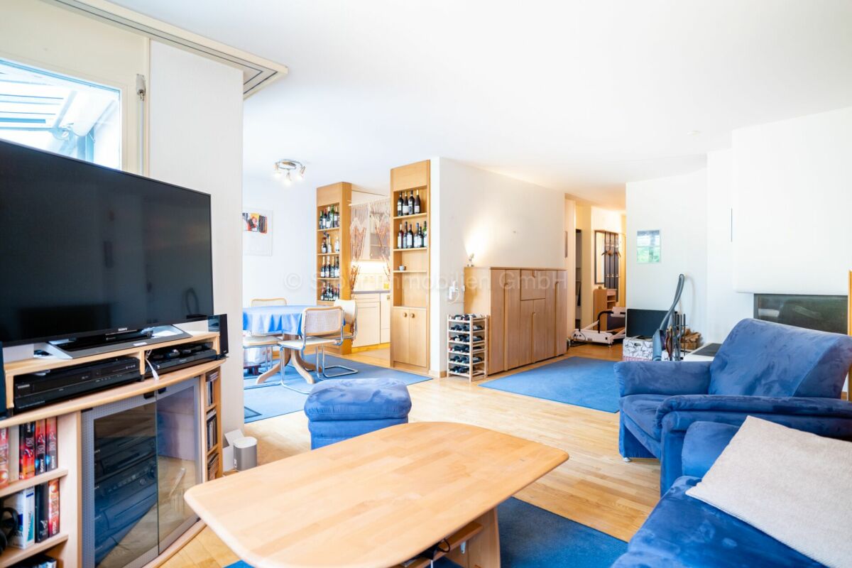 Heller Wohnbereich mit Fernseher und blauem Sofa