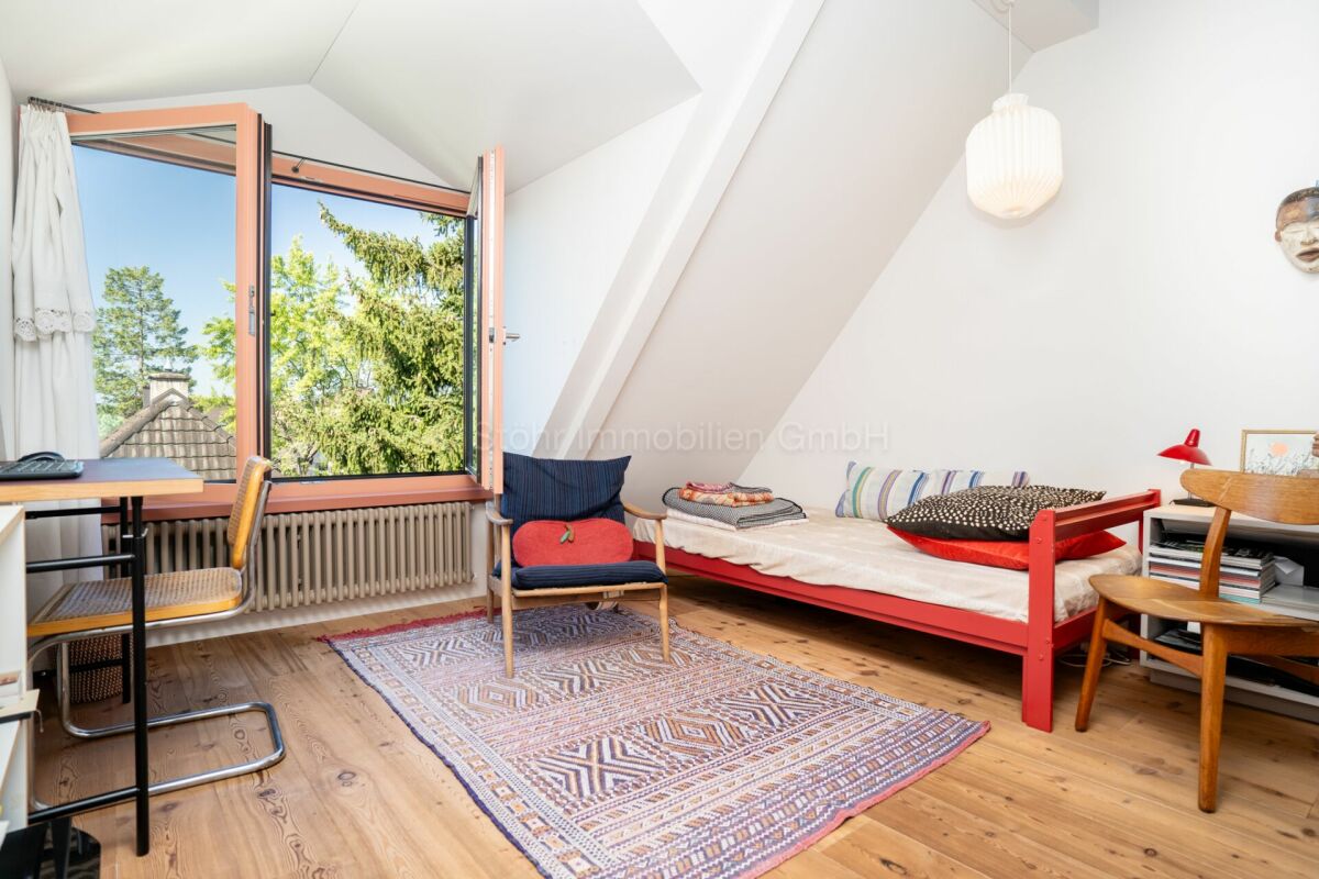 Dachzimmer mit Bett und großem Fenster