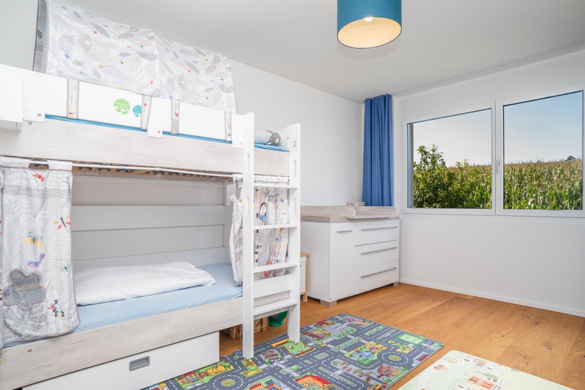 Kinderzimmer mit Etagenbett und großem Fenster
