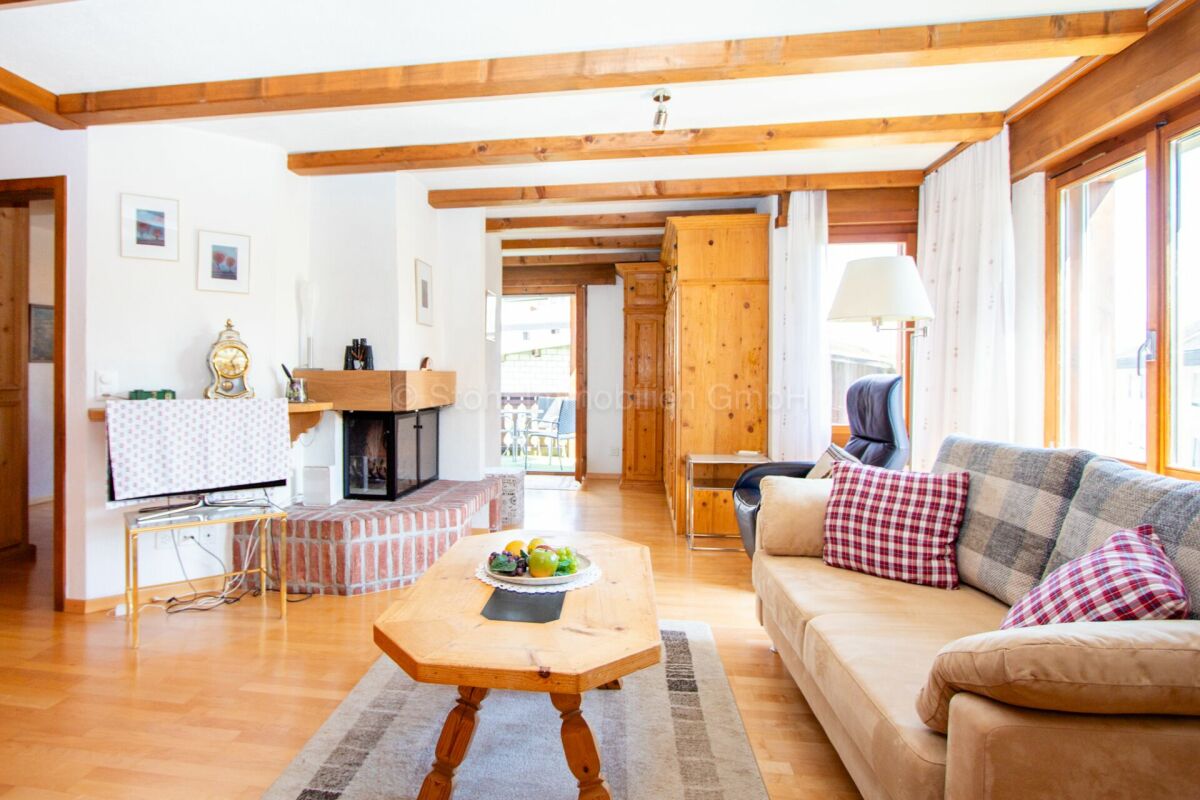 Helles Wohnzimmer mit sichtbaren Holzbalken und Kamin