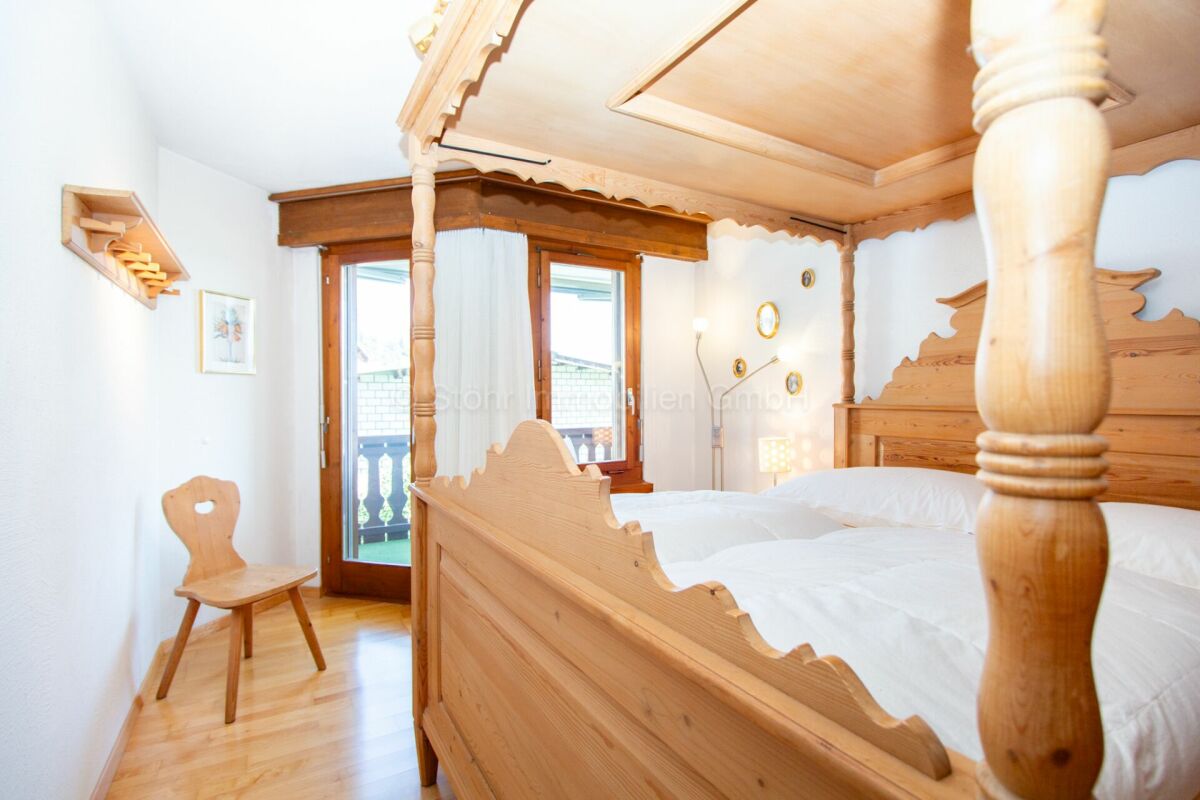 Schlafzimmer mit Holz-Doppelbett und Balkonblick