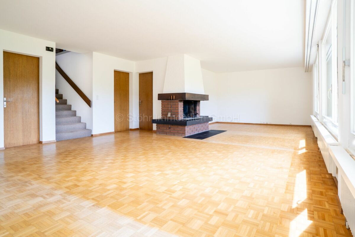 Großer leerer Wohnraum mit Kamin und Parkett