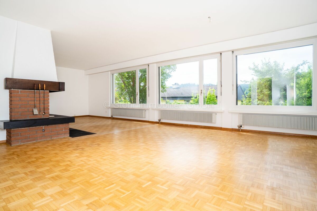 Großer Wohnraum mit Kamin und Panoramafenstern