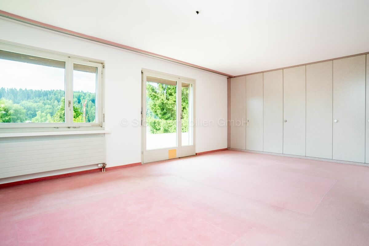 Heller leerer Raum mit großem Fenster und Balkon-/Terrassentür sowie Einbauschränken