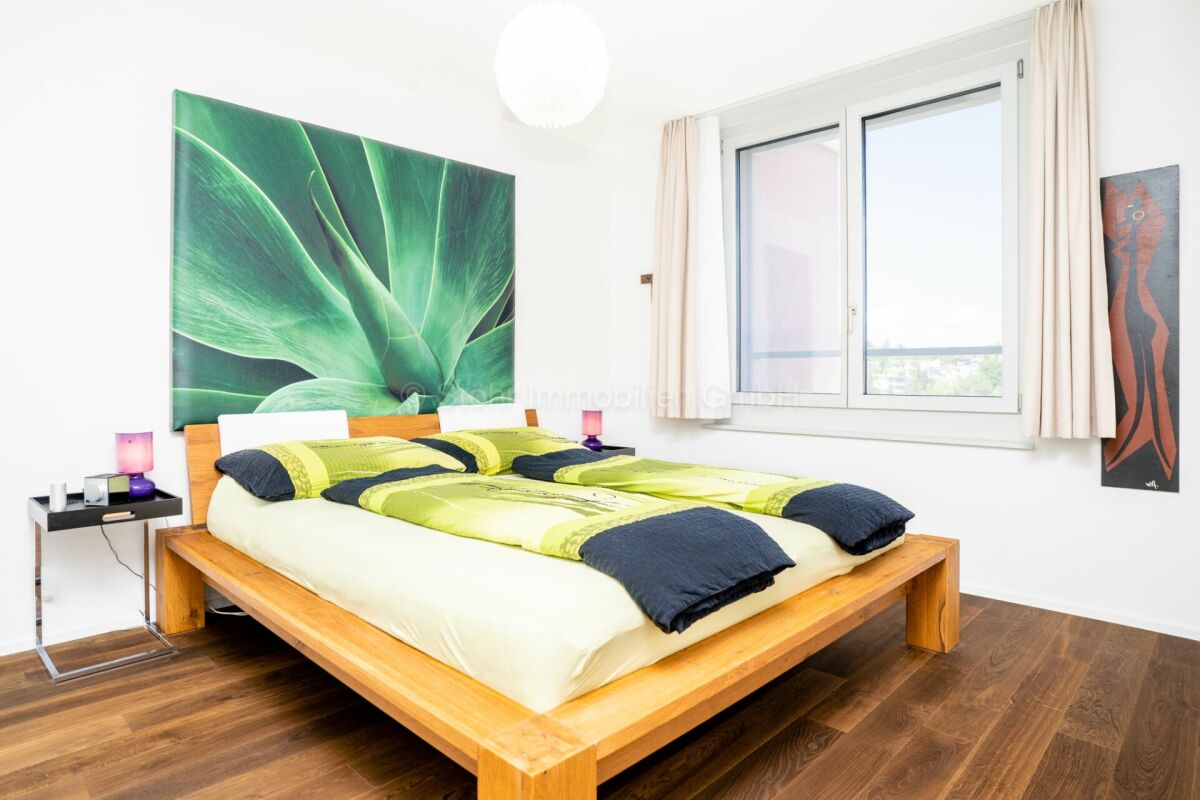 Helles Schlafzimmer mit großem Fenster und Holzbett