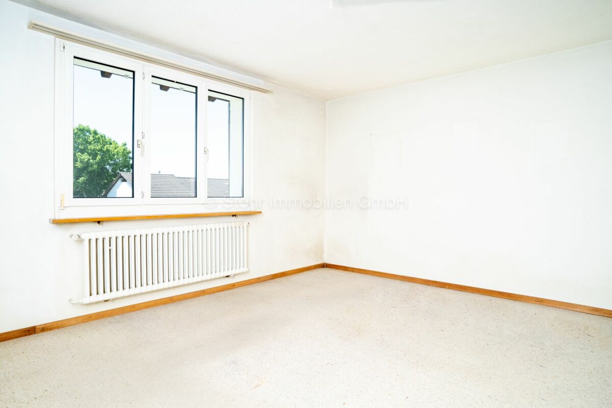 Leerer, heller Raum mit Fenster und Heizkörper