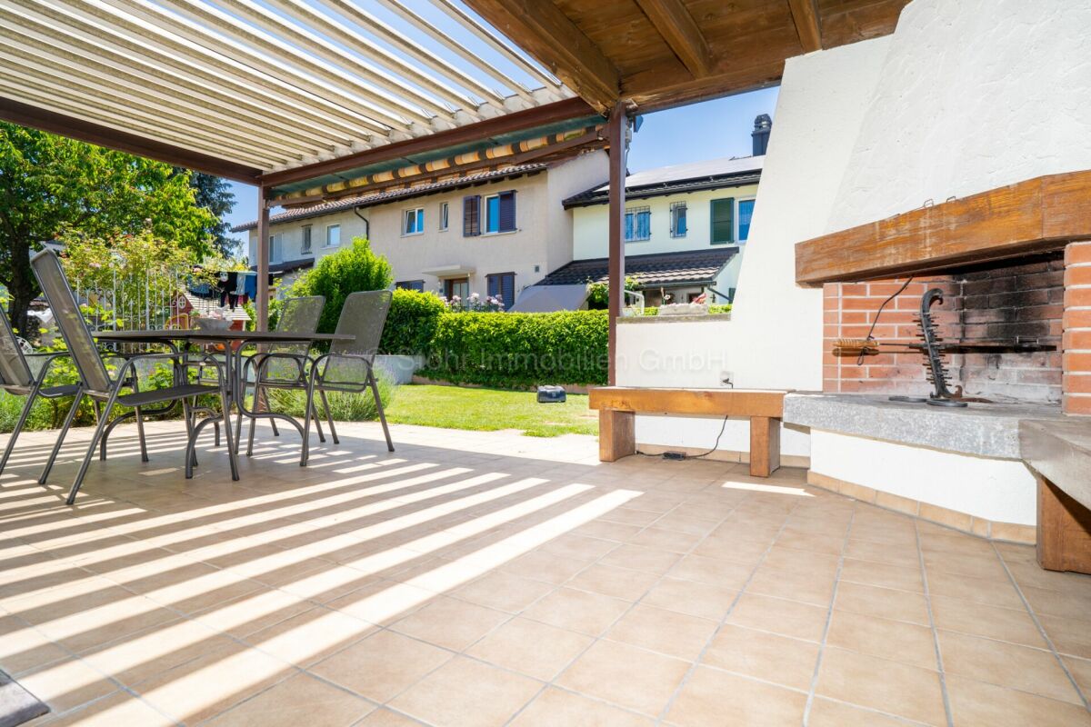 Überdachte Terrasse mit Grill und Gartenblick