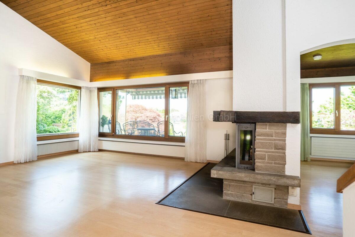 Heller Wohnraum mit Kamin und großen Fenstern