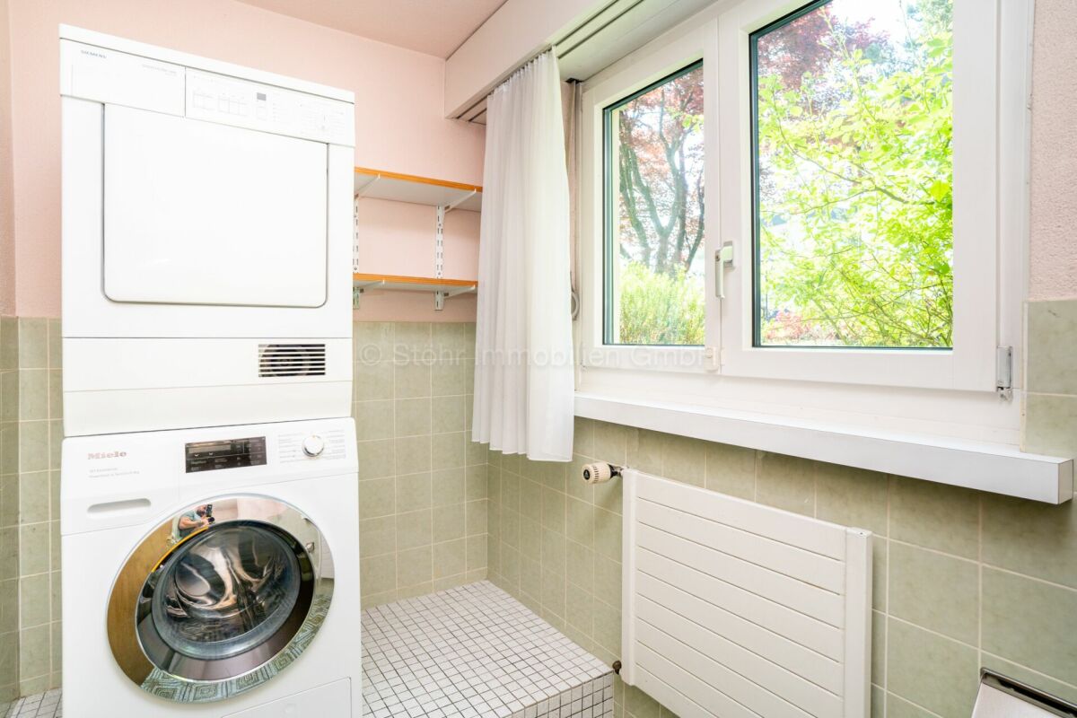 Hauswirtschaftsraum mit Waschtrockner und Fenster