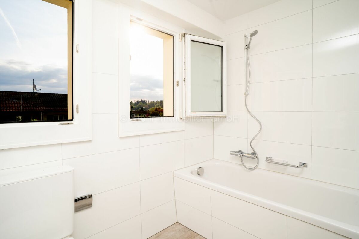 Helles Badezimmer mit Badewanne und Fenstern
