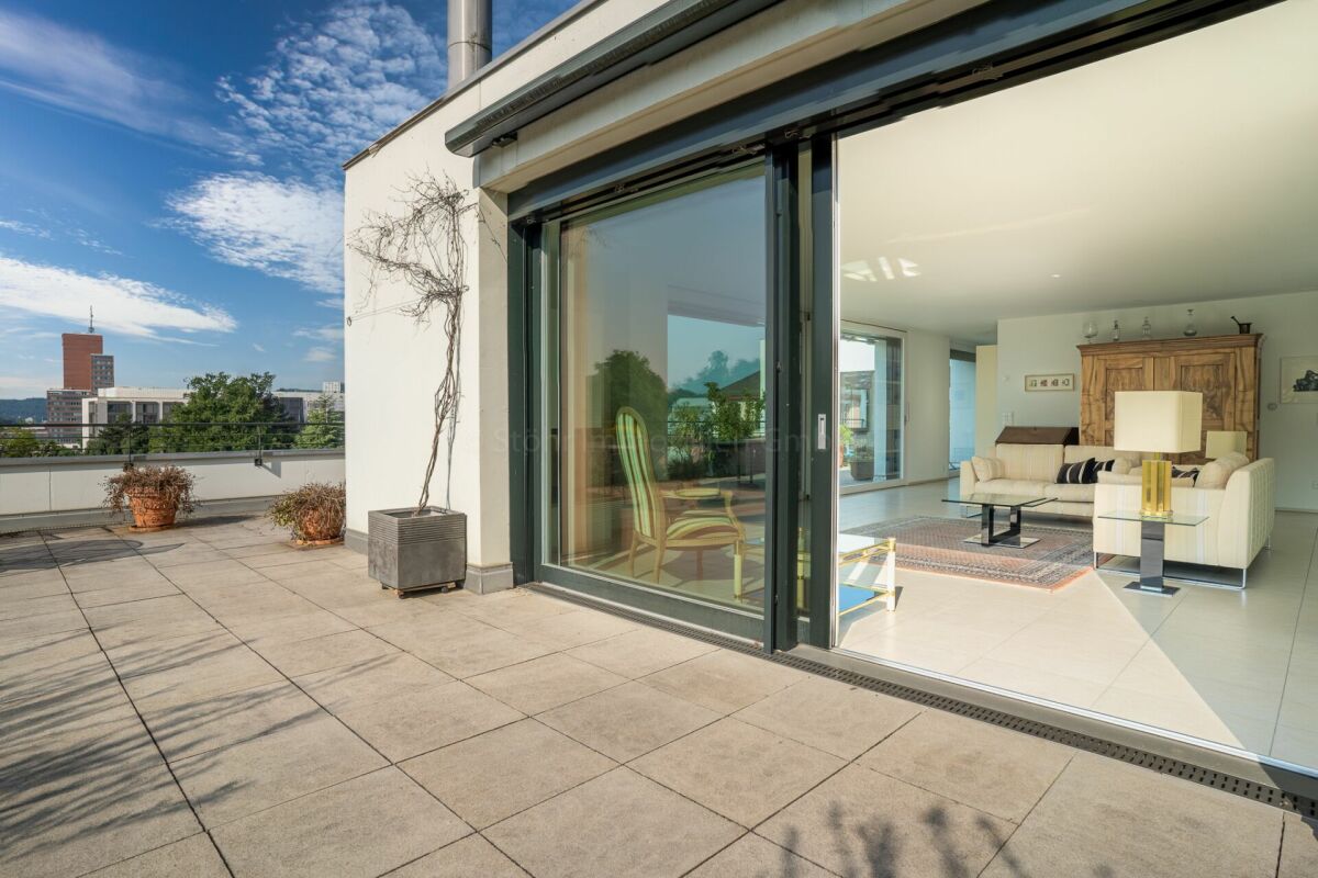Dachterrasse mit Blick in einen hellen Wohnbereich