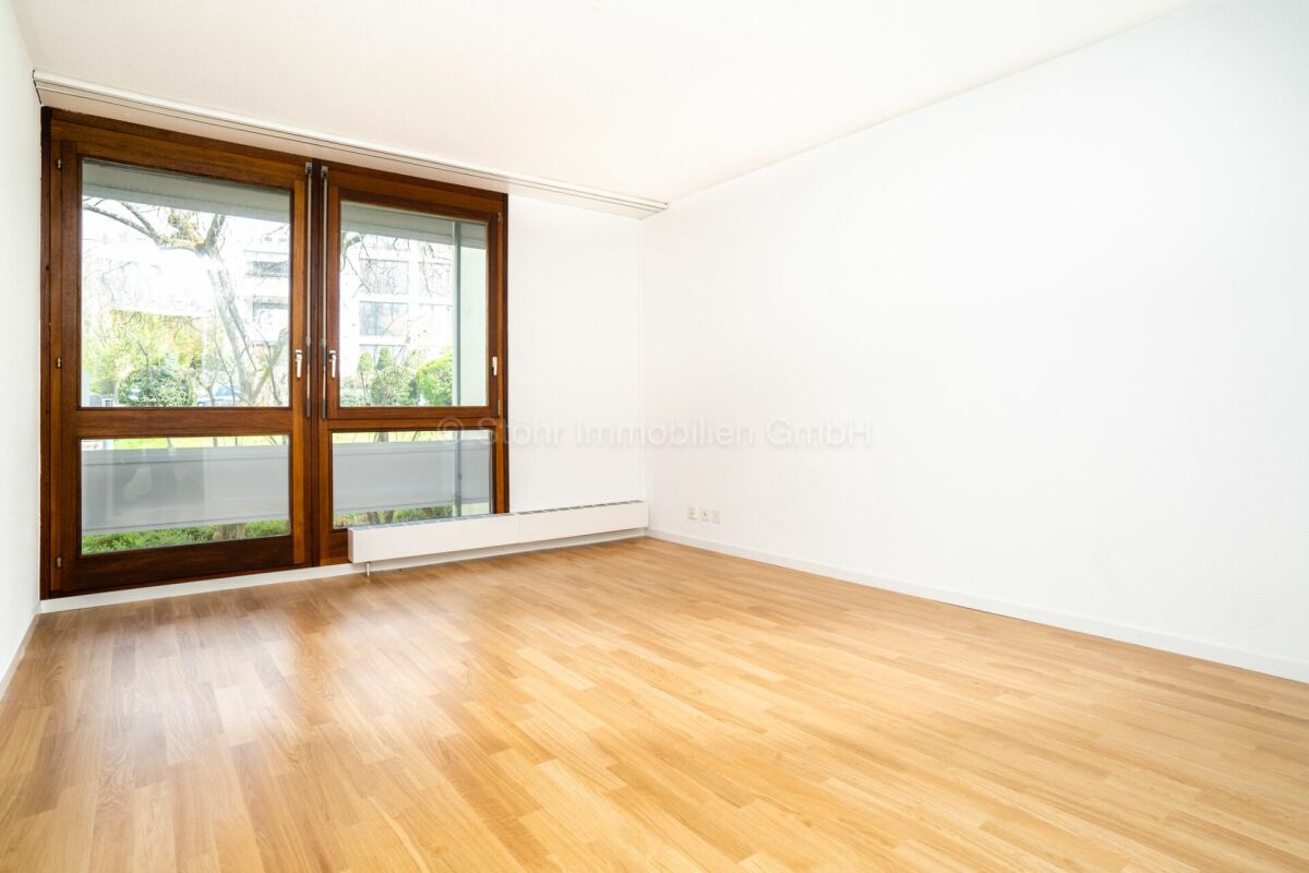 Heller leerer Wohnraum mit Holzfenstern und Parkettboden