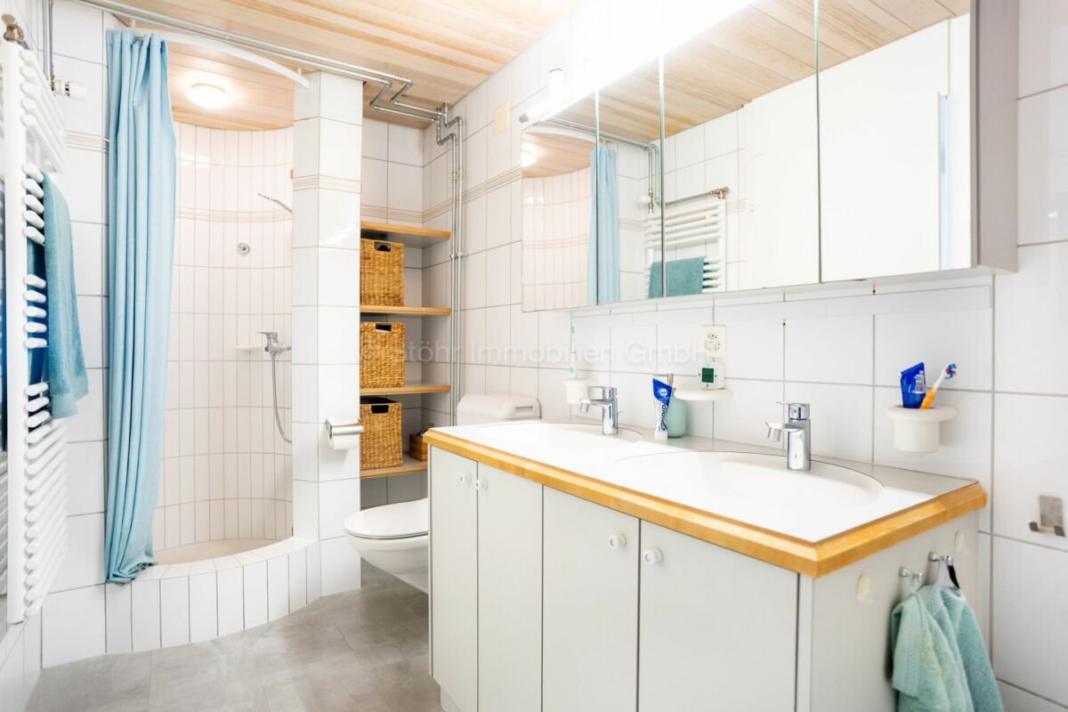 Helles Badezimmer mit Doppelwaschtisch und Duschbereich