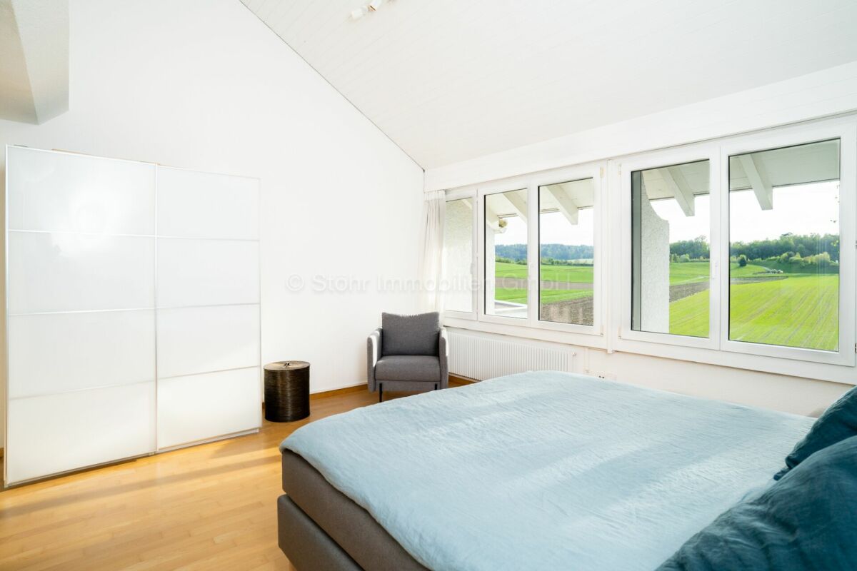 Helles Schlafzimmer mit Panoramafenstern und Grünblick
