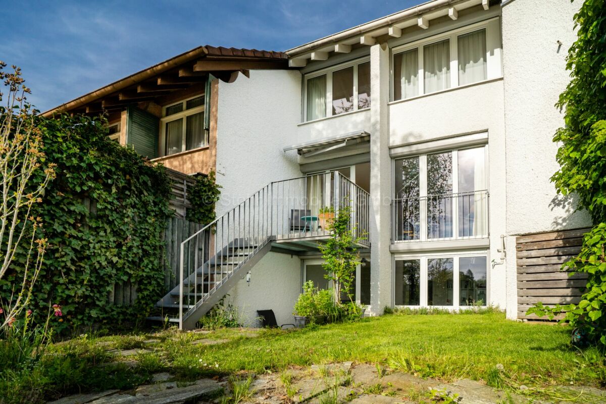 Weiße Hausfassade mit Balkon und Gartentreppe