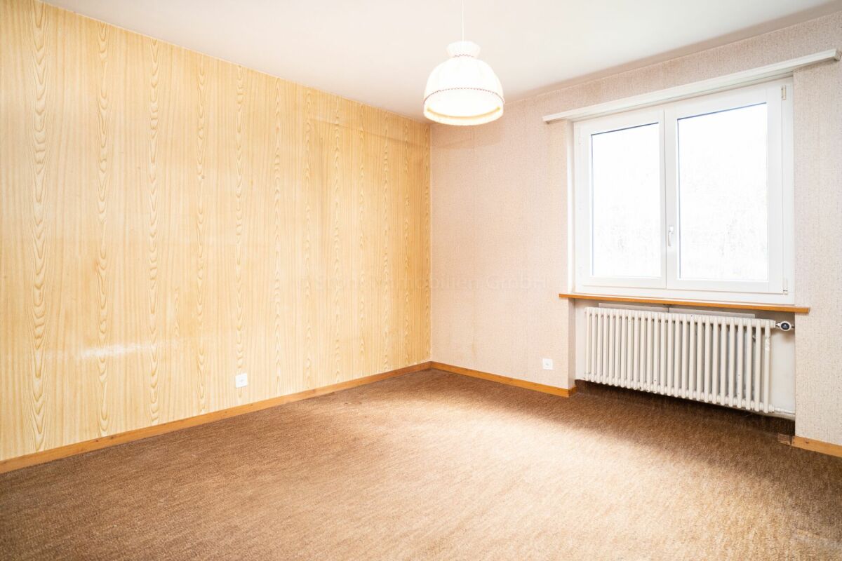 Leeres Zimmer mit Holzpaneelwand und Heizkörper unter dem Fenster