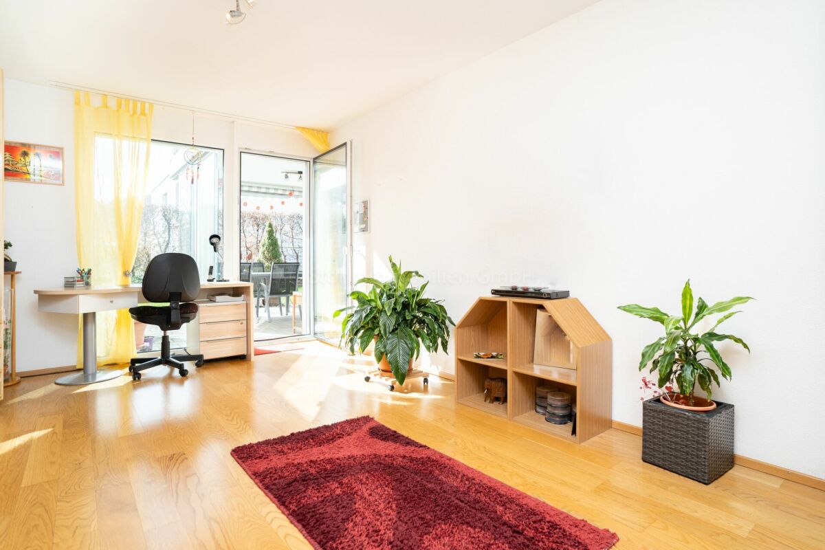 Heller Wohnraum mit Schreibtisch und Balkonzugang