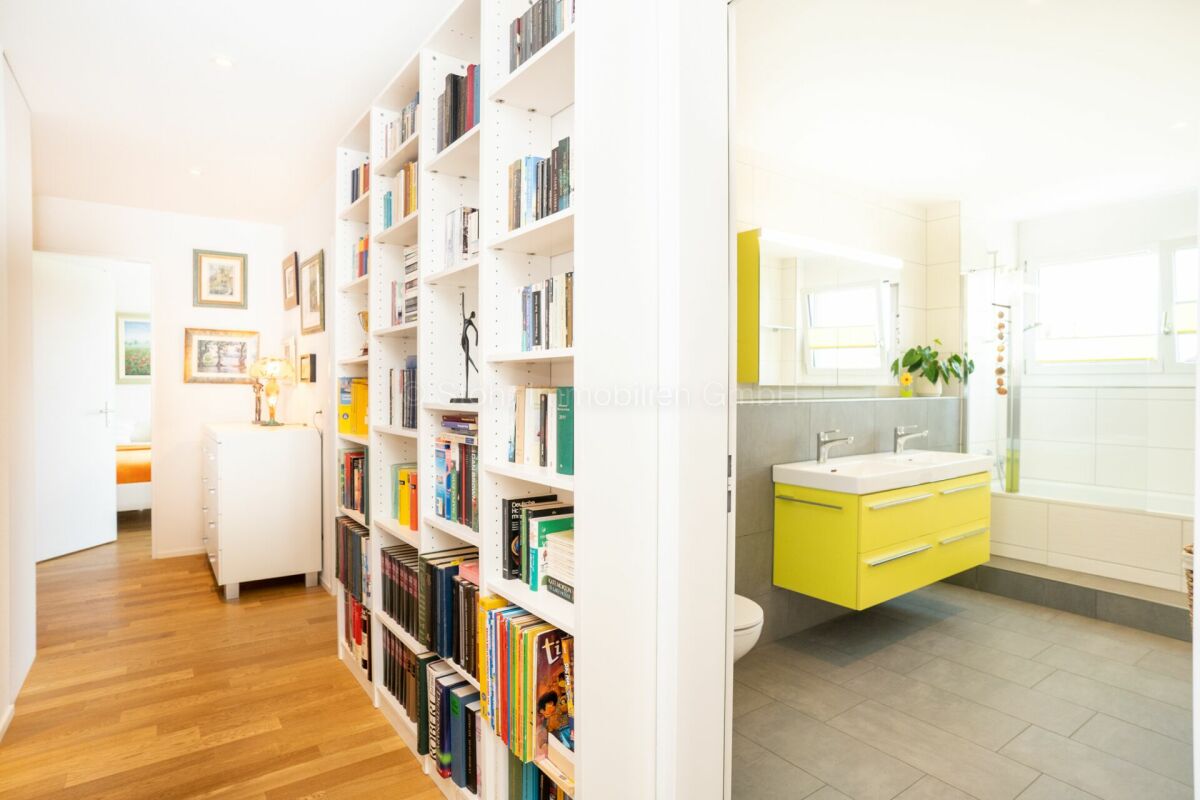 Heller Flur mit Bibliotheksregal und angrenzendem Badezimmer