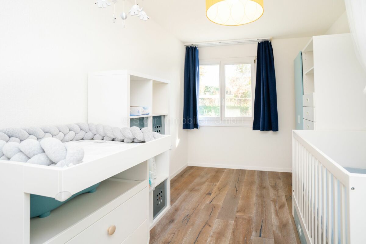 Helles Kinderzimmer mit Fenster und weißen Möbeln