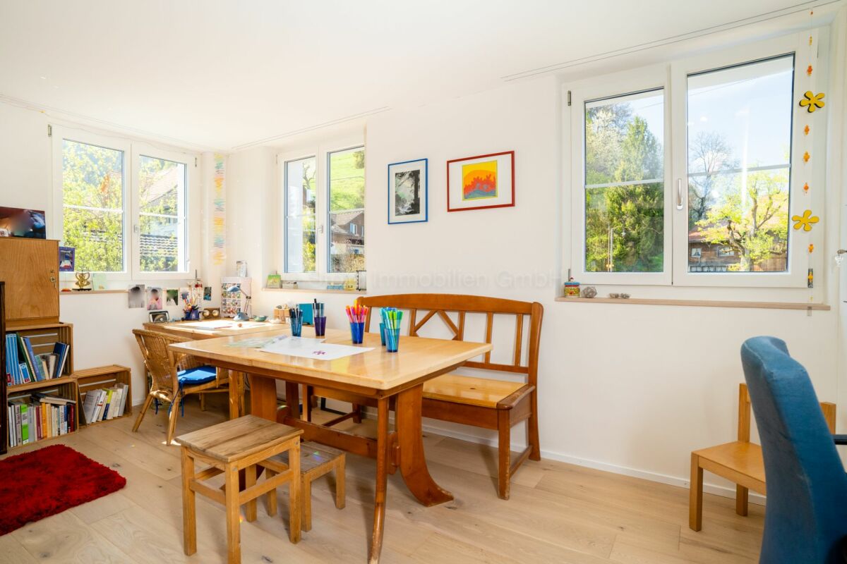 Helles Kinder- bzw. Arbeitszimmer mit Holztisch und vielen Fenstern