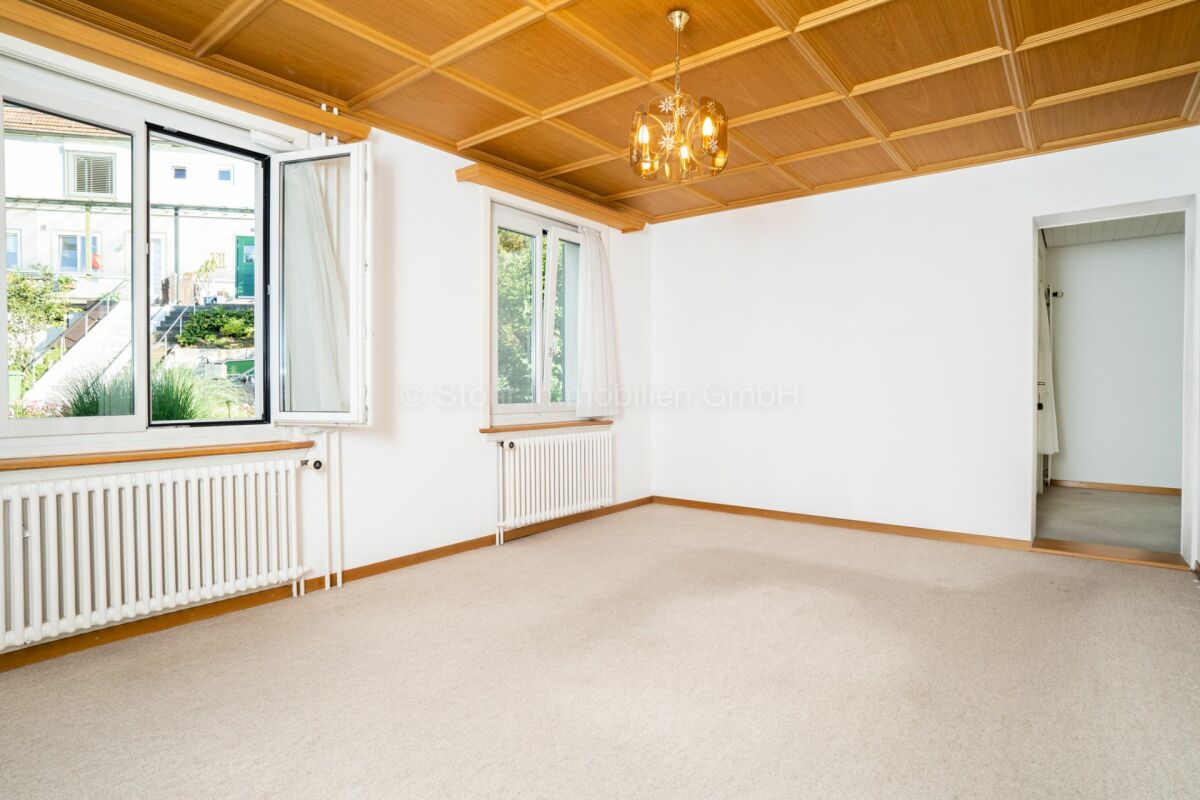 Heller leerer Wohnraum mit Holzdecke und großen Fenstern
