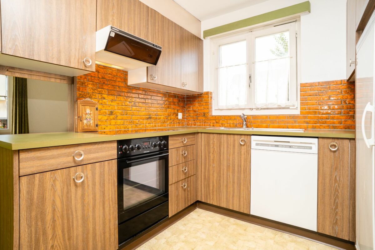 Kleine Küche mit Holzoptik und orangefarbener Fliesenrückwand