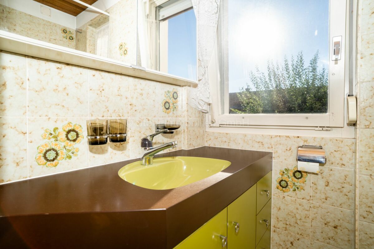 Badezimmer mit grünem Waschbecken und Blumenfliesen