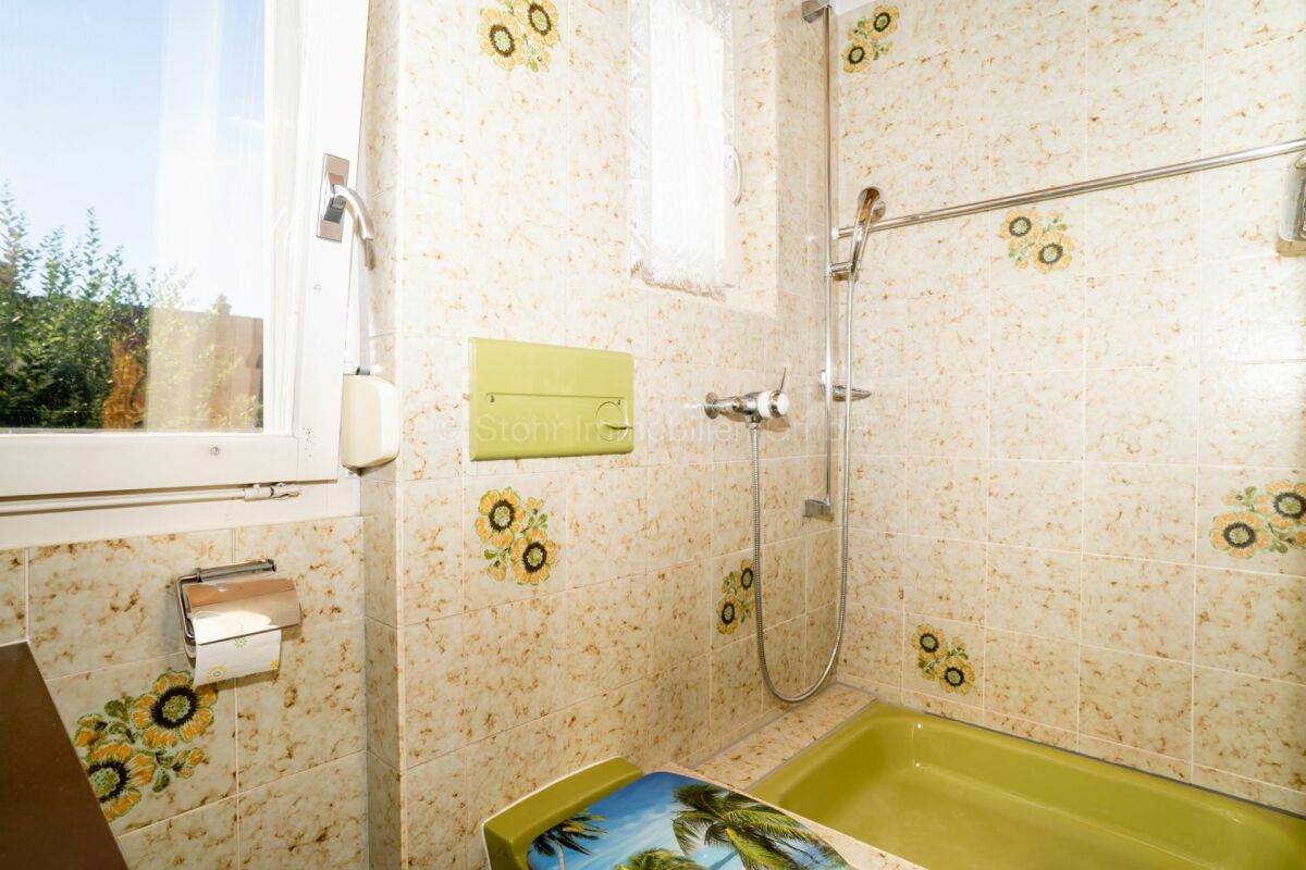 Badezimmer mit gefliester Wanne und Fenster
