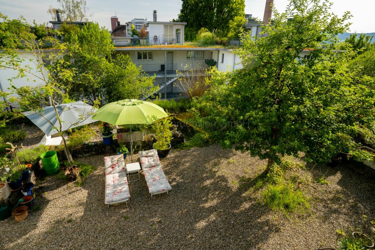 Garten mit Liegen und Sonnenschirmen