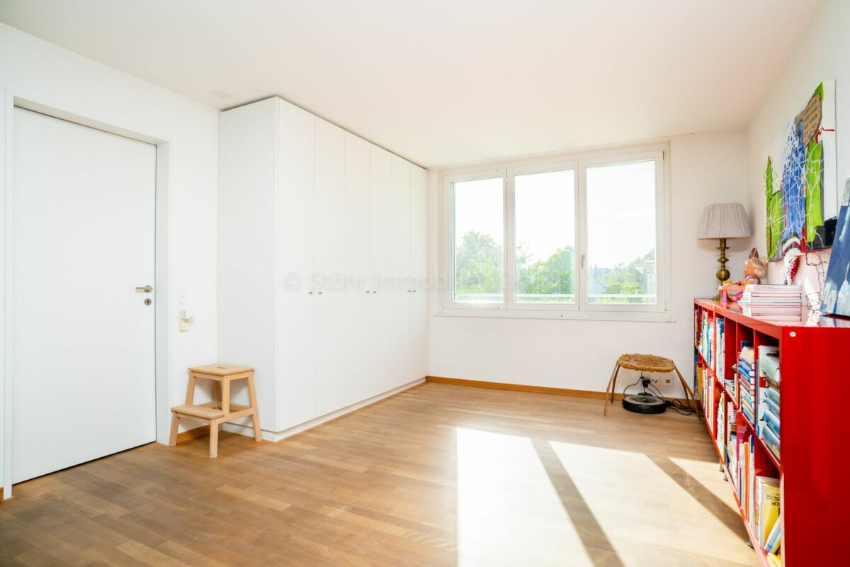 Helles Kinder- oder Arbeitszimmer mit großem Fenster und Einbauschrank