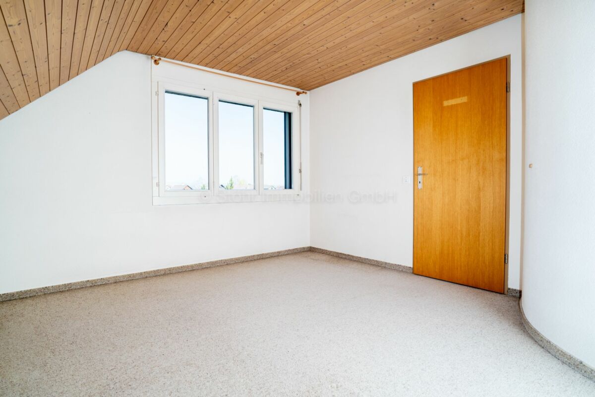 Helles, leeres Dachgeschosszimmer mit Holzdecke